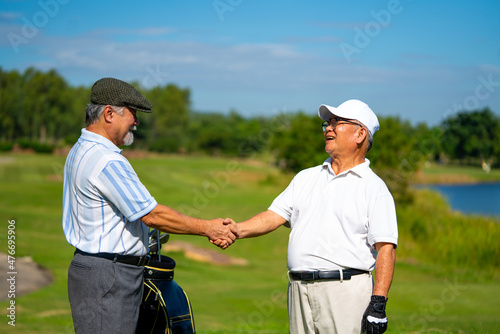 Asian people businessman and senior CEO shaking hand after finish talking business project and game at golf course. Elderly male friends golfer enjoy outdoor sport golfing together at country club.