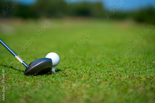 Close up of Asian man golfer hand holding golf club hitting golf ball on the green at golf course. Healthy male enjoy outdoor lifestyle activity sport golfing at country club on summer vacation