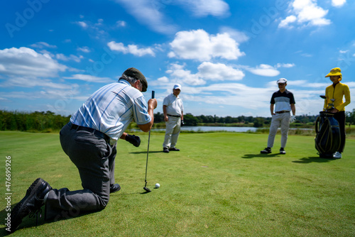 Group of Asian people businessman and senior CEO golfing near the hole on golf fairway together at country club. Healthy elderly man golfer enjoy outdoor golf sport and leisure activity with friends. photo