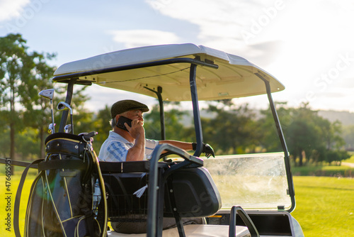 Asian senior businessman sitting on golf cart with talking on mobile phone working corporate business while golfing with at country club. Elderly male golfer enjoy outdoor sport in summer vacation. © CandyRetriever 