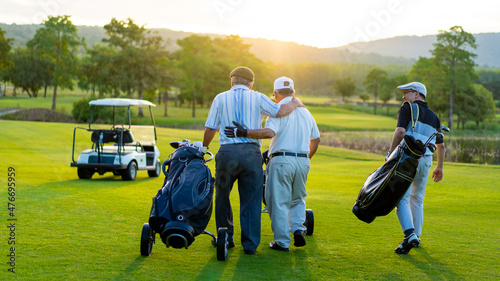 Group of Asian people businessman and senior CEO enjoy outdoor sport golfing together at country club. Healthy men golfer holding golf bag walking on fairway with talking together at summer sunset