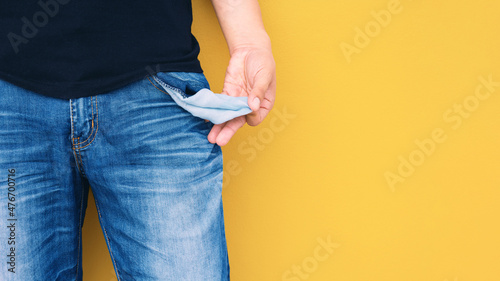 Konstfotografi Man showing his empty pocket on yellow wall background.