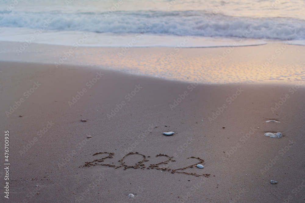 2022 Happy New Year inscription sand beach. The written text is written on yellow sand and is washed away by a wave. The concept of changing the year, the holiday. Mockup postcards copy space 2022 Happy New Year inscription sand beach. The written text is written on yellow sand and is washed away by a wave. The concept of changing the year, the holiday. Mockup postcards copy space