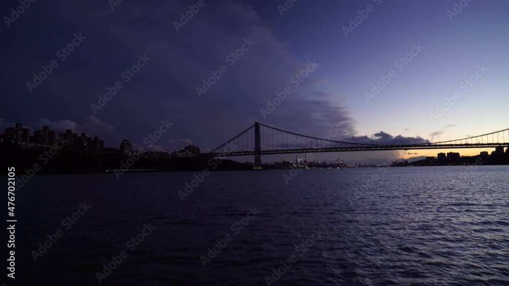New York city skyline and Manhattan suspension Bridge at dusk, view from East River. panning shot New York city skyline and Manhattan suspension Bridge at dusk, view from East River. panning shot