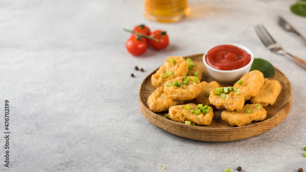 Golden chicken nuggets in wooden plate, sprinkled with green onions and a lemon wedge. Pub menu. Copy space