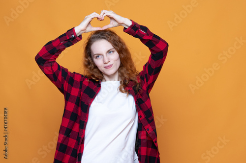 young girl in a plaid shirt with glasses on an orange background © Екатерина Елисафенко