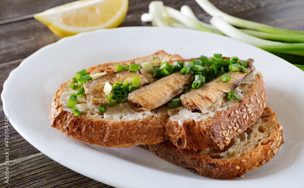 Smorrebrod with sprats, butter and green onions. Close-up.