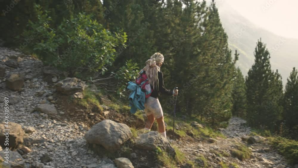 Blonde hiker woman trekking, trekking poles, Benasque, Spain, slow motion wide shot Blonde hiker woman trekking, trekking poles, Benasque, Spain, slow motion wide shot