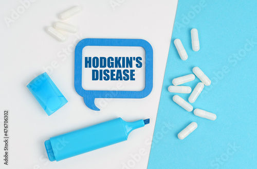 On a white and blue table are pills, a marker and a blue plaque with the inscription - Hodgkin s disease