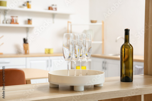 Bottle of wine and tray with glasses on shelf in modern kitchen