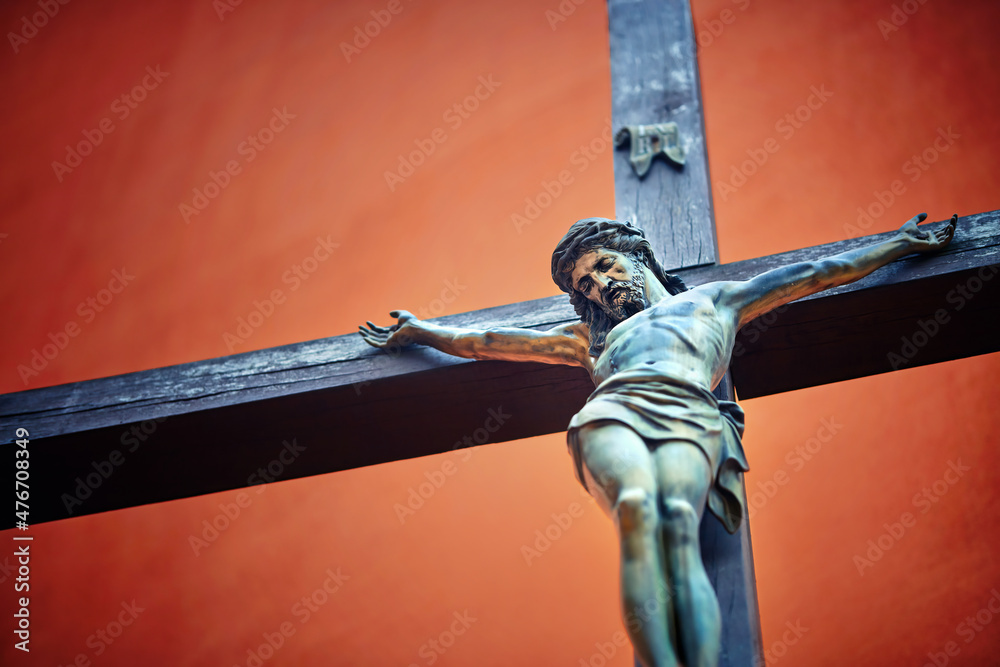 Catholic cross with crucified Jesus Christ statue over rough background