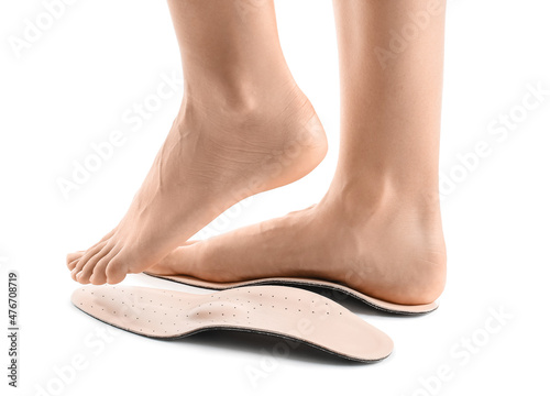 Female feet and orthopedic insoles on white background