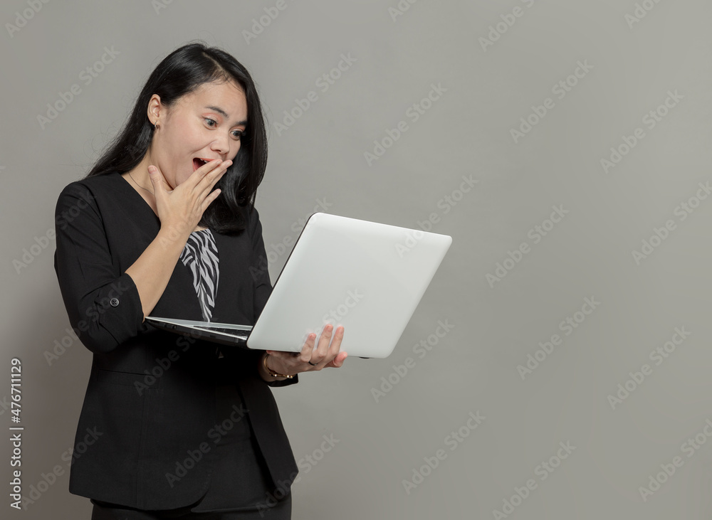 Shocked business woman holding and looking at laptop screen Shocked business woman holding and looking at laptop screen