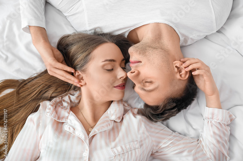 Happy couple lying on bed in morning, top view