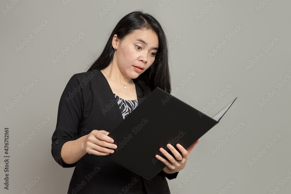 Young woman in suit with dumbfounded expression while holding and looking at folder Young woman in suit with dumbfounded expression while holding and looking at folder