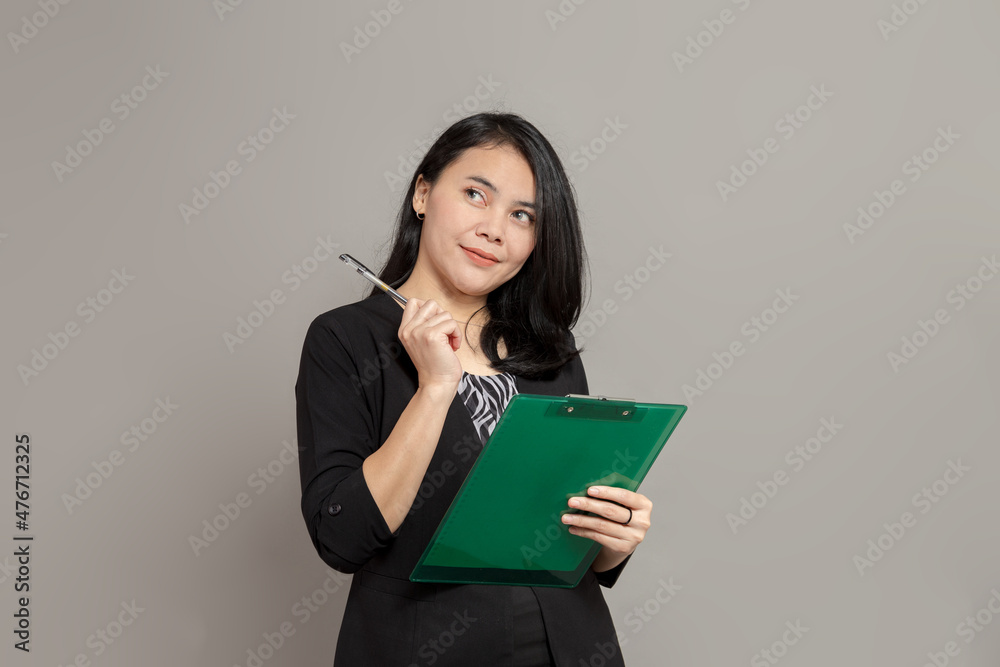 Beautiful woman is imagining while holding a pen and clipboard Beautiful woman is imagining while holding a pen and clipboard