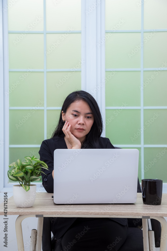 Beautiful woman working on laptop with hand on chin Beautiful woman working on laptop with hand on chin