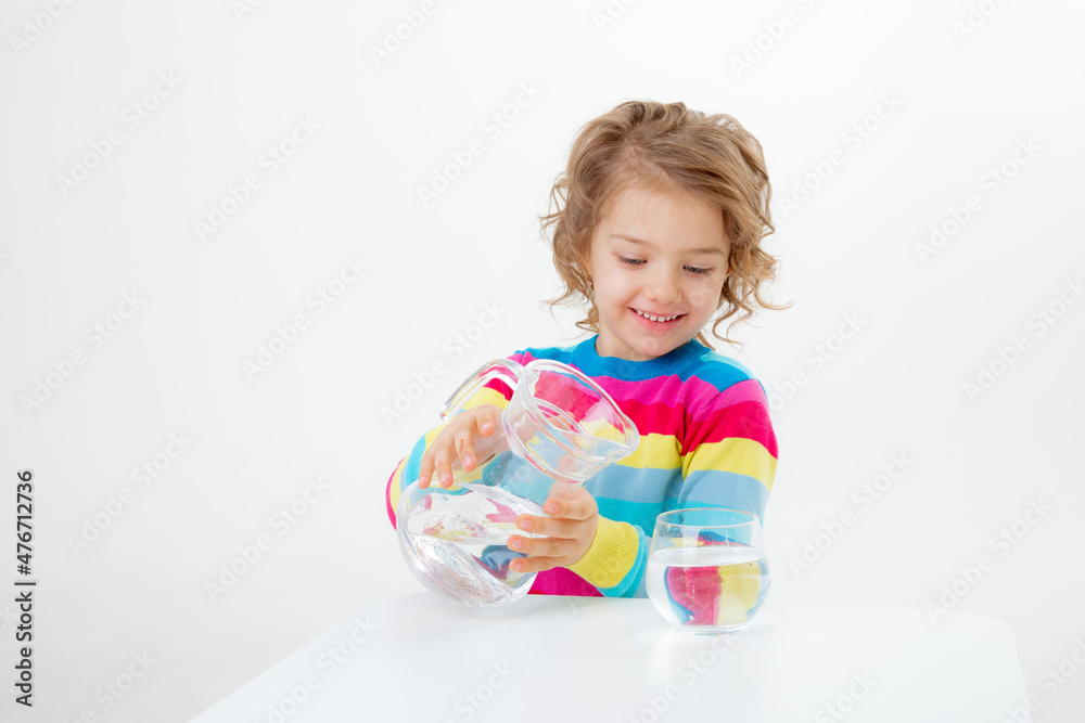 a little cute girl holds a jug of water, pours water into a glass isolated on a white background a little cute girl holds a jug of water, pours water into a glass isolated on a white background