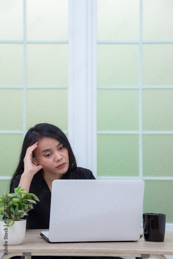 Business woman sitting on chair looking at laptop screen with confused expression Business woman sitting on chair looking at laptop screen with confused expression
