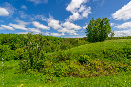 Spring photography, meadows, fields, ravines, hills, rural landscape. A deep, narrow gorge with steep slopes. A naturally raised area of ​​land, not as high or craggy as a mountain.