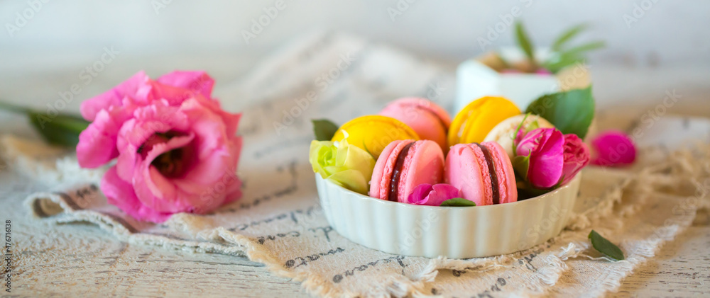 Good morning. Delicious macarons desserts are served on the table in the morning for breakfast. Beautiful light still life with a rose highlight. Baking for breakfast on a light table with copy space