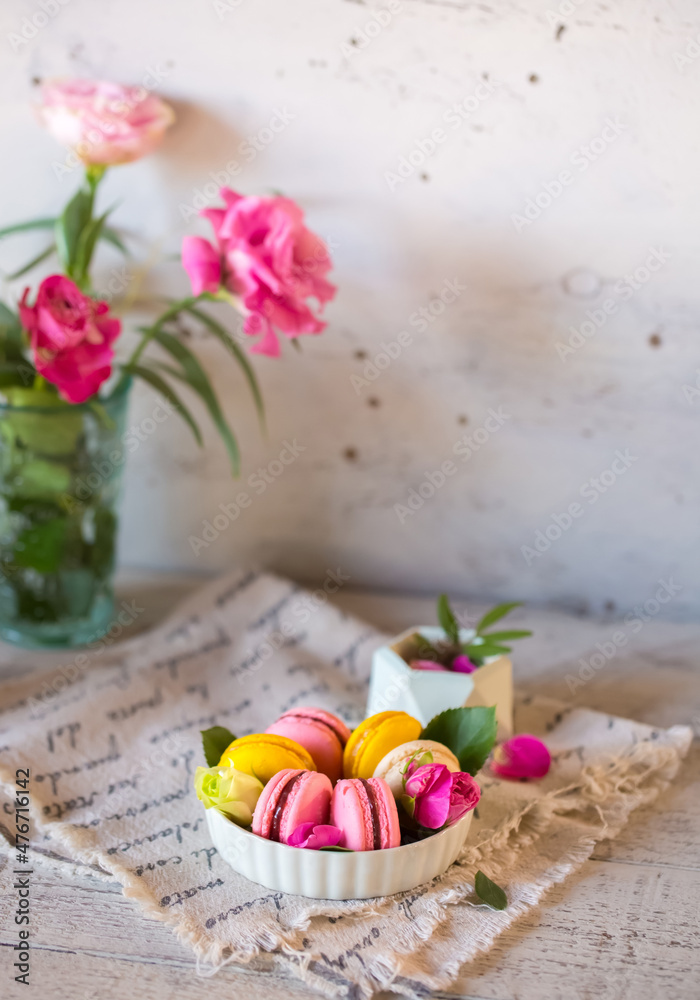 Good morning. Delicious macarons desserts are served on the table in the morning for breakfast. Beautiful light still life with a rose highlight. Baking for breakfast on a light table with copy space