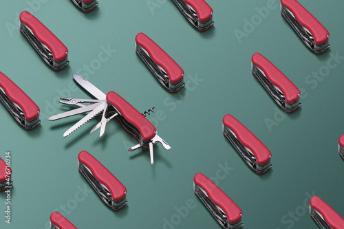 Pattern made with  multifunctional  folding swiss knifes red color on green background. One knife decomposed. photo
