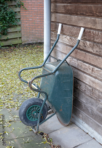 Weathered wheelbarrow leaning against a wooden wall Fotobehang