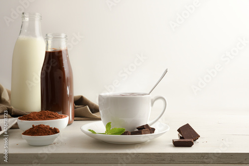 Hot chocolate cup with chunks and powder and bottles isolated