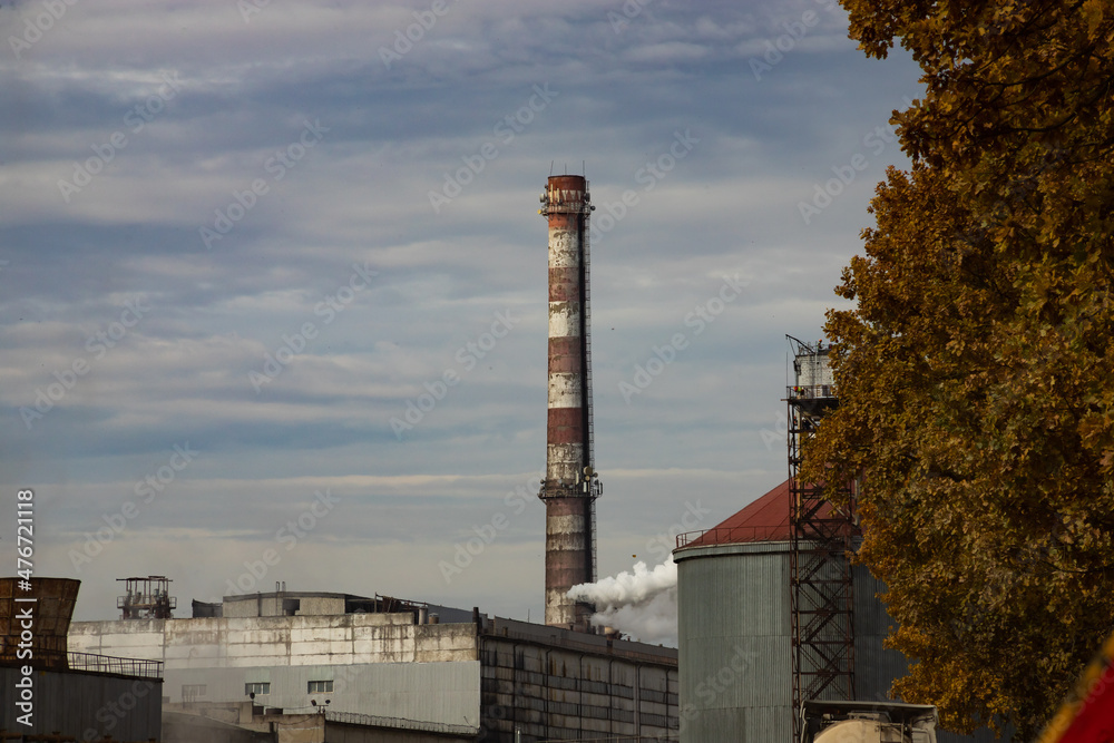 Industrial building with chimneys near the road in autumn