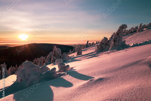 Sunset over the winter landscape from the top of a snowy hill. Winter landscape in the Czech Republic.
