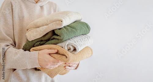Woman\'s hand holding a stack of clothes. Clothes Donation, Renewable Concept.Preparing Garment at Home before Donate. Woman packs clothes for a donation or for moving