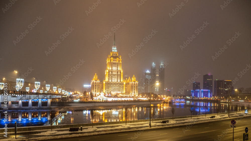 Illuminated high-rise stalinist building near river at winter night in Moscow, Russia. Historic name is Hotel Ukraine.