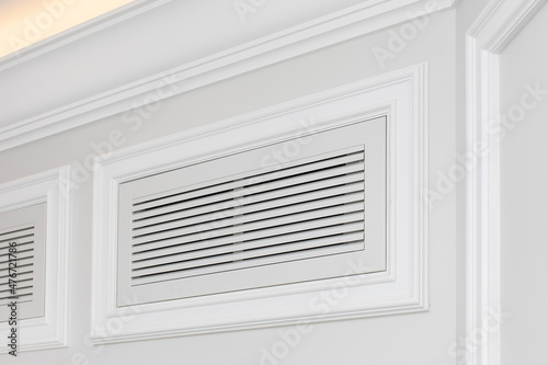 Ventilation grate of conditioning system decorated and disguised with classic white moldings in modern interior.