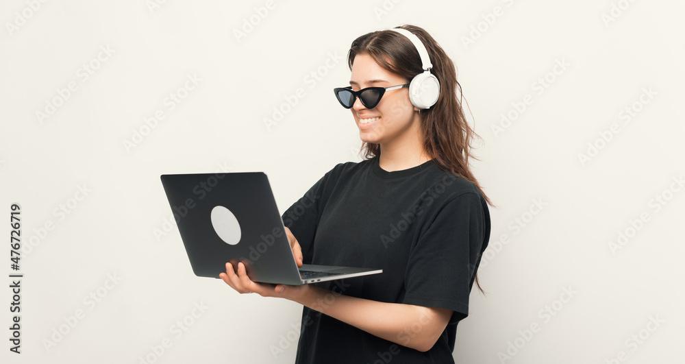 Happy young woman in cool sunglasses, using a laptop and headphones, technology concpet Happy young woman in cool sunglasses, using a laptop and headphones, technology concpet