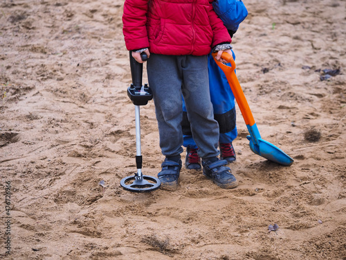 a boy in a sandbox looking for treasure with a metal detector