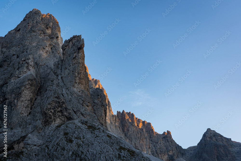 sun touching the mountains of pale di san martino in the dolomites alps