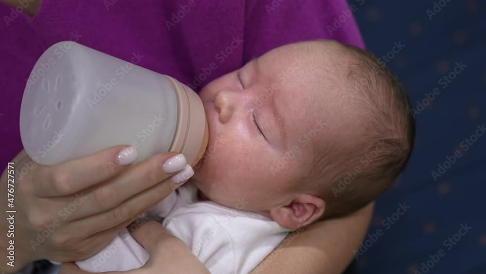 Toddler eating milk from bottle and closing sleepy eyes. Baby gradually falling asleep while eating. Close up. Toddler eating milk from bottle and closing sleepy eyes. Baby gradually falling asleep while eating. Close up.
