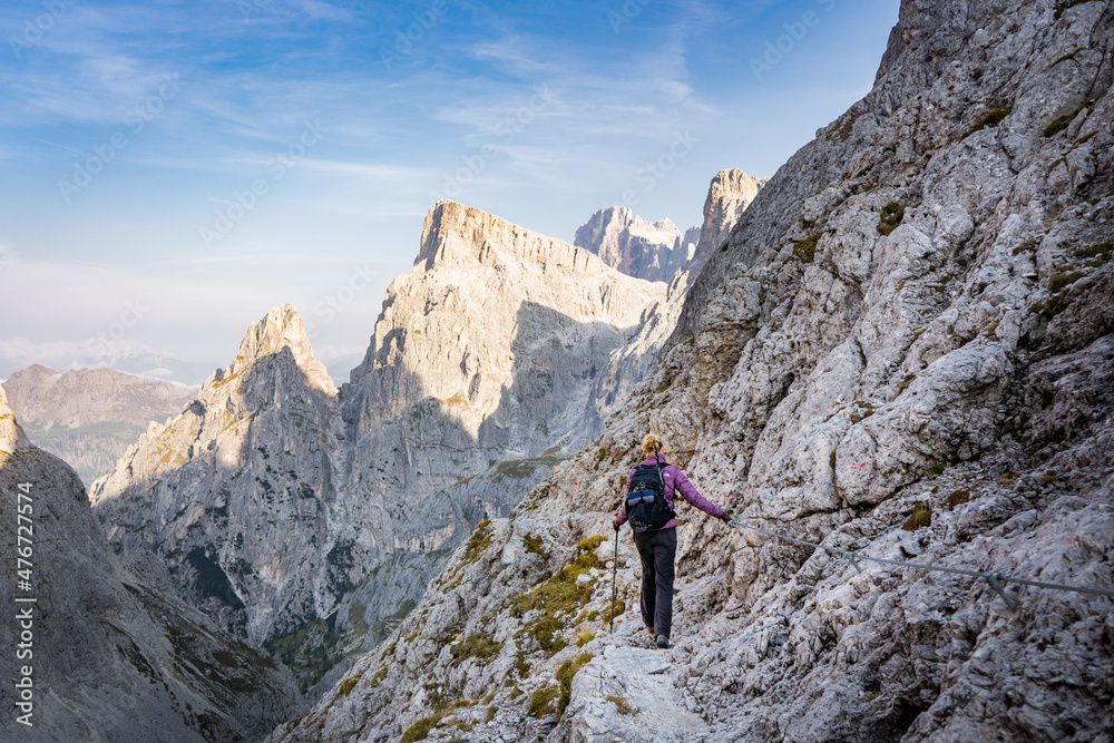 woman hiking on trekking trail in the pale di san martino on a sunny day in the dolomites