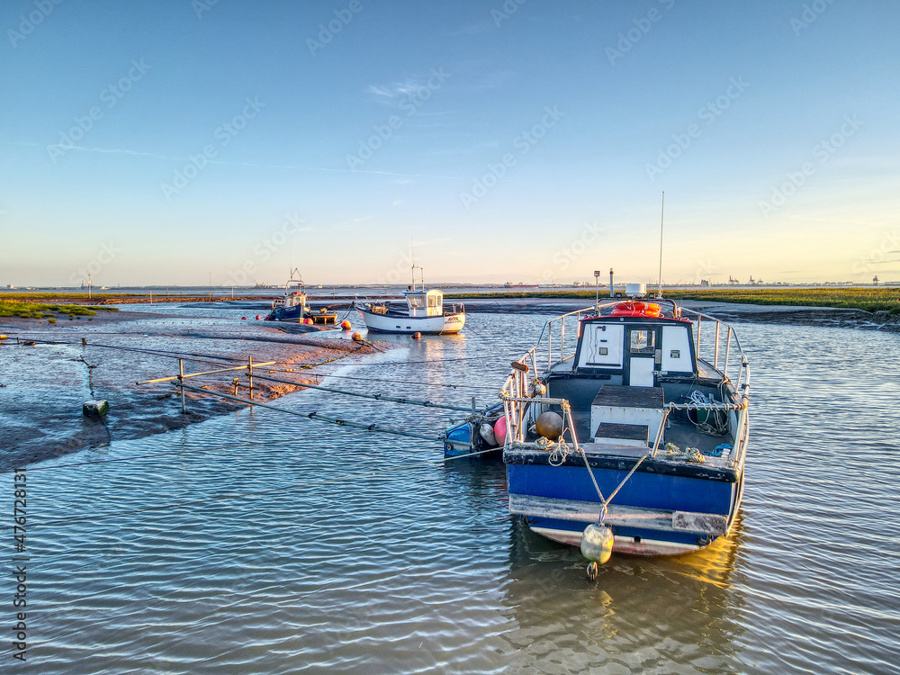 Fototapeta premium Small fishing boats moored at low tide at Stone Creek inlet, Sunk Island, East Yorkshire, UK