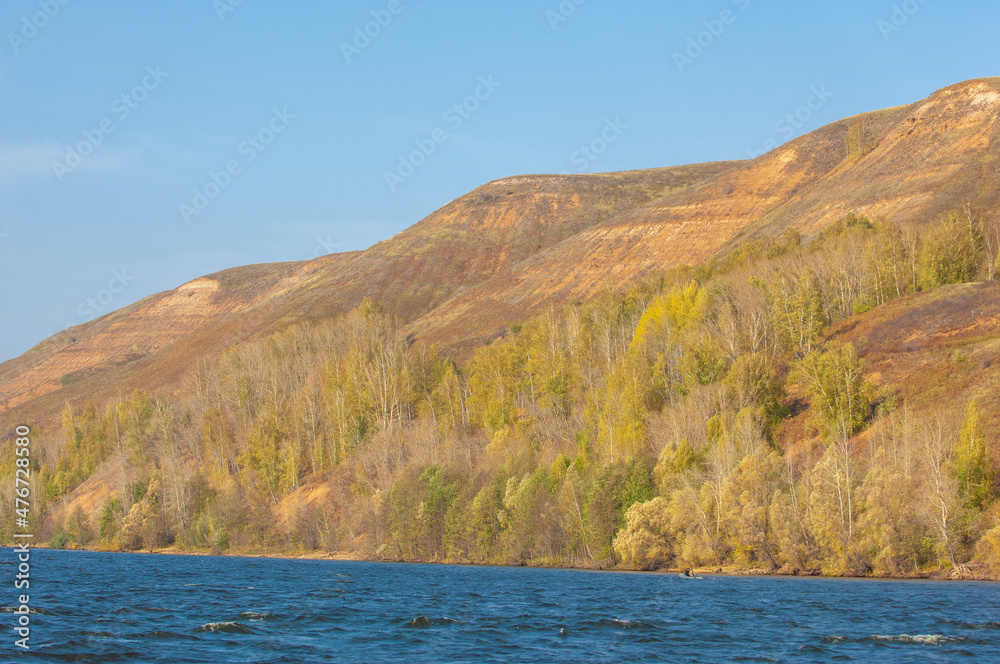 utumn landscape, autumn view of the Kama. Fantastic autumn scene with bright sky, majestic rocky mountains and bright trees glowing with sunlight