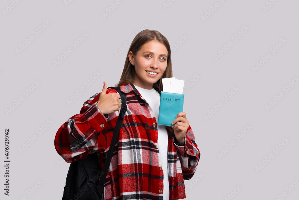 Traveler tourist fun woman in checkered shirt hold on passport with tickets show thumb up like gesture Traveler tourist fun woman in checkered shirt hold on passport with tickets show thumb up like gesture