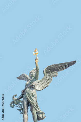 Photography Cover page with statue of beautiful angel with wings at the top of column on the Cechuv Most Bridge in Prague, Czech Republic, portrait, details, at blue sky solid background with copy space