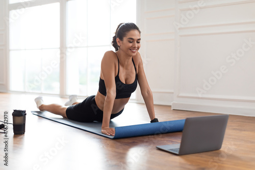 Young woman stretching back on mat with pc