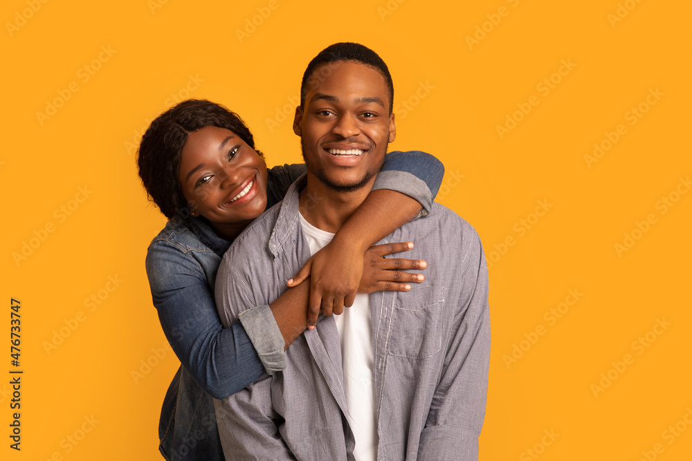 Obraz premium Portrait of young cheerful black couple hugging and smiling at camera