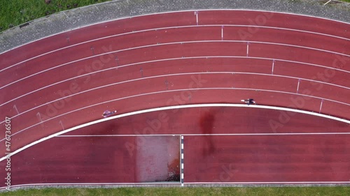 Drone aerial top down shot of 2 women running on athletic track