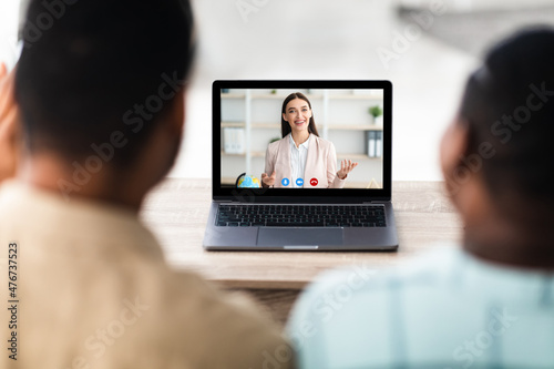 African American Couple Consulting Distantly Via Video Call Indoor, Rear-View