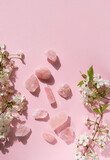 Rose quartz minerals set and white flowers on pink background. gemstones for esoteric spiritual relax practice, Magic Crystal Ritual, Witchcraft, open Chakra. Feng Shui, reiki therapy. top view
