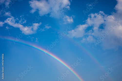 Beautiful rainbow with blue sky and clouds. © chirawan_nt