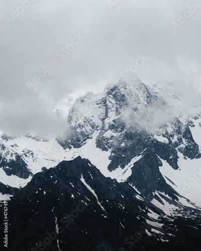 Snow on top of the mountain, beautiful photography of the foggy sky and winter mountains. Outdoor view, rocky cliff. Winter tourism.